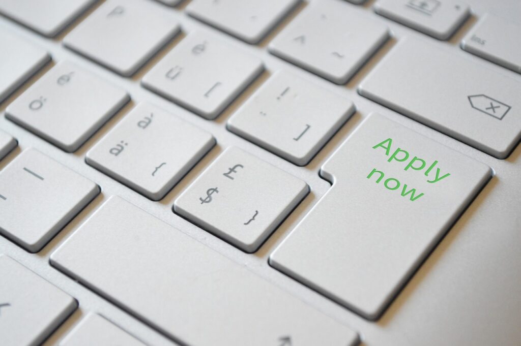 Laptop keyboard with an "Apply Now" button.